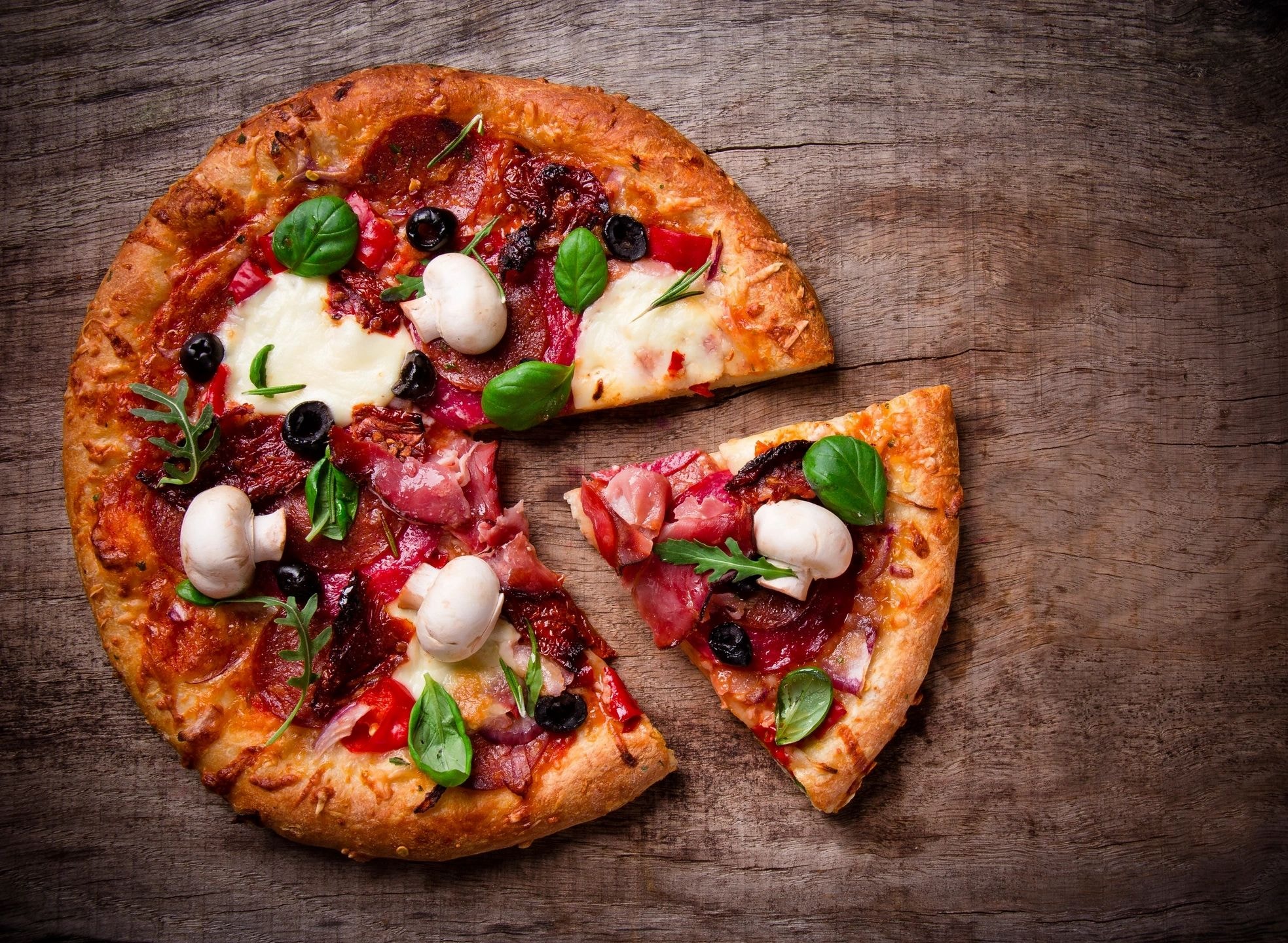 Sliced Italian pizza with cured meats and mozzarella